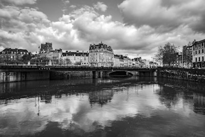 Black and white photo of Prague's Charles Bridge shrouded in morning mist, capturing quiet reflections on the Vltava River.