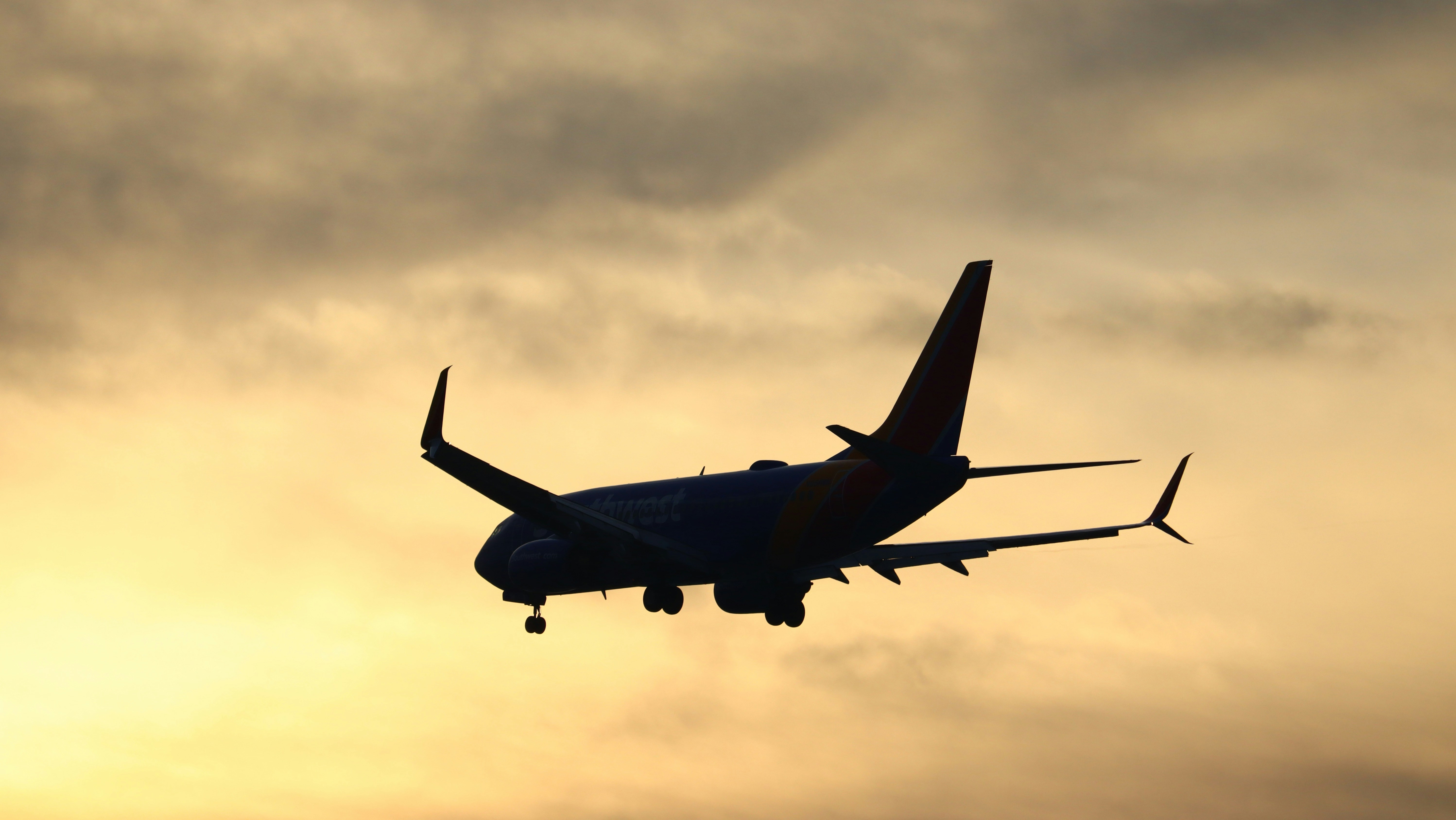 a large jetliner flying through a cloudy sky, A Southwest 737 on final approach