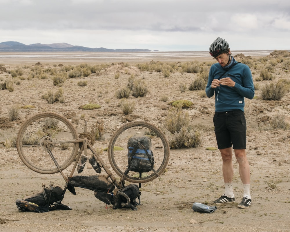 a man standing next to a bike in the desert