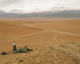 a man standing next to a tent in the desert
