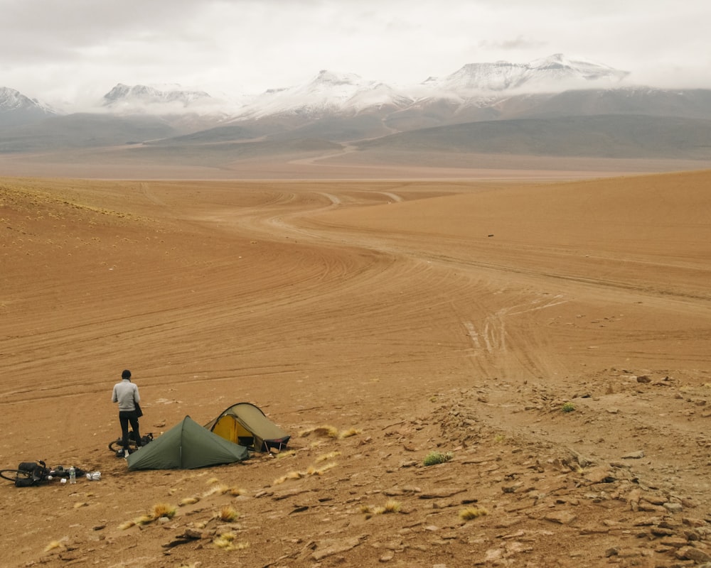 a man standing next to a tent in the desert