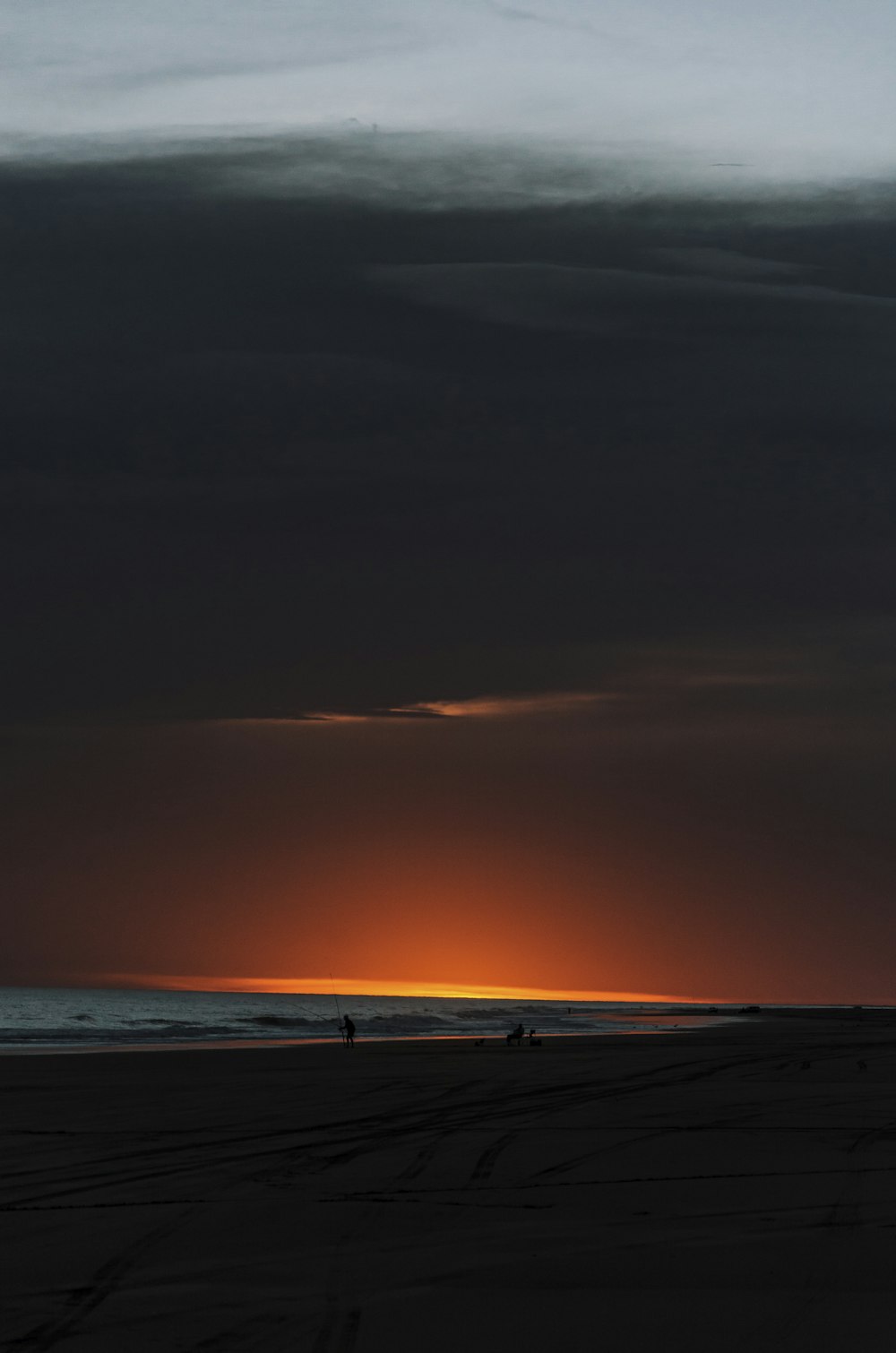 the sun is setting over the ocean on a cloudy day