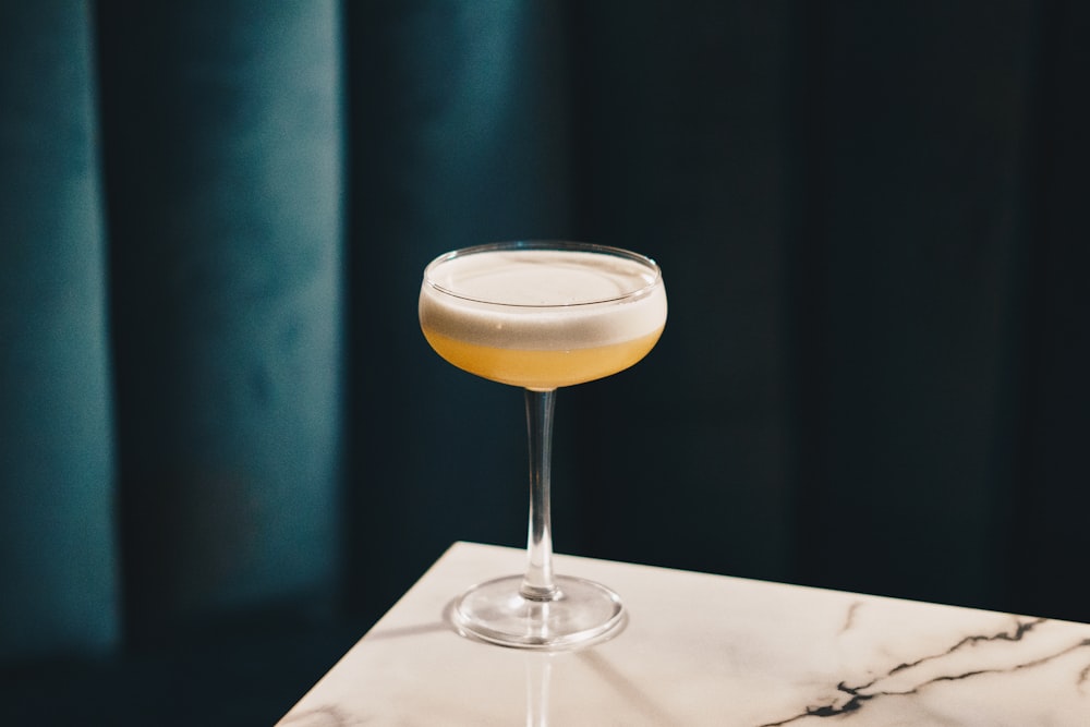 a glass filled with a drink sitting on top of a table