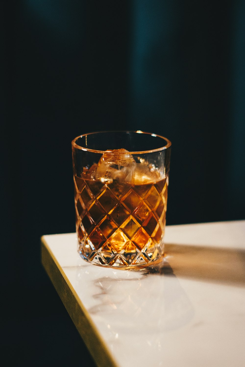 a glass of whiskey sitting on top of a counter