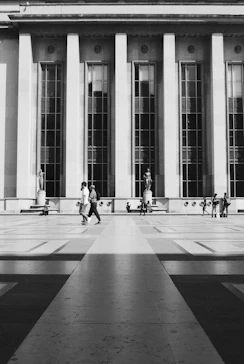 a black and white photo of people walking in front of a building