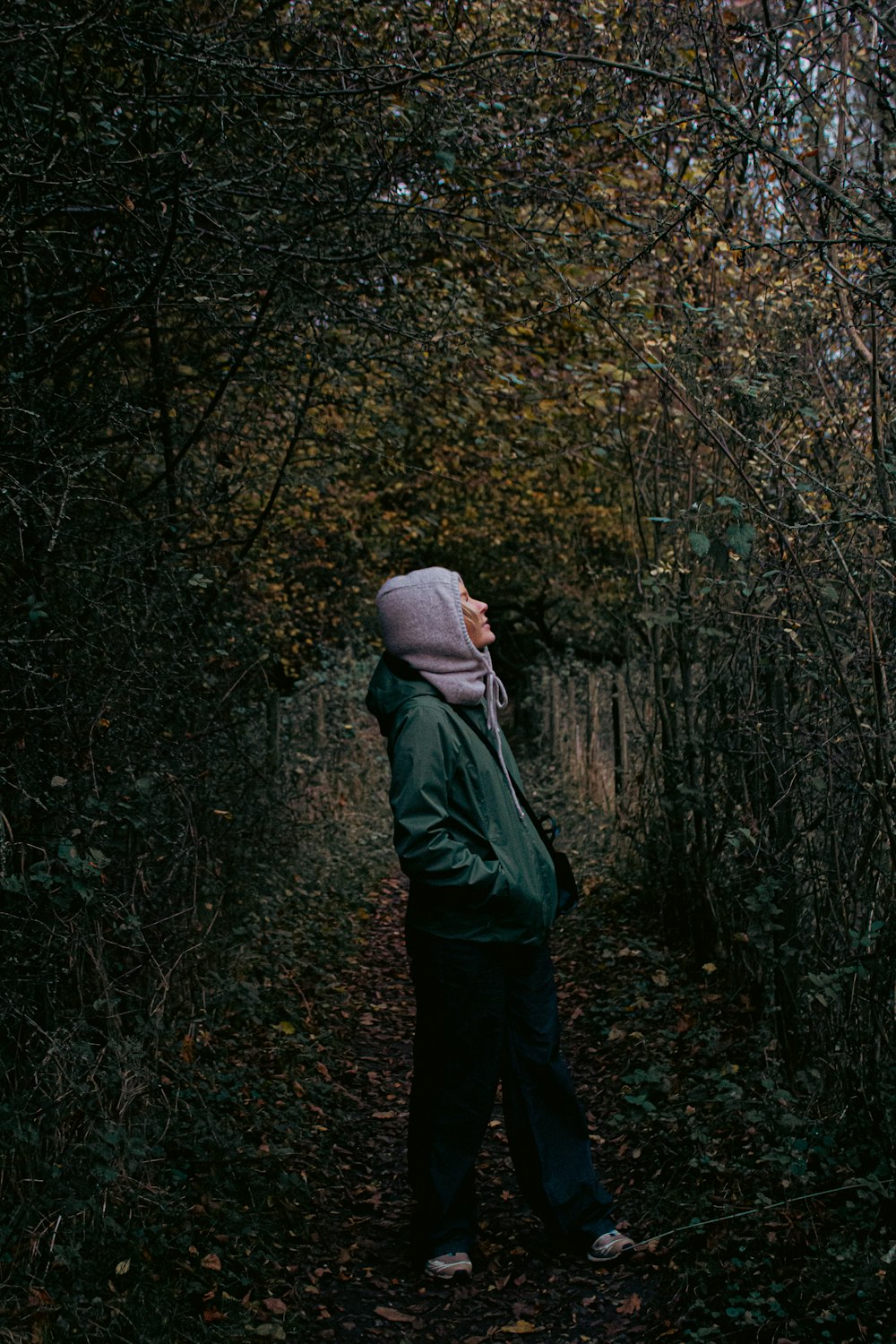 a person in a hooded jacket standing in a wooded area