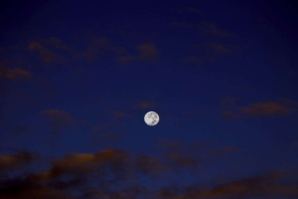 a full moon in the night sky with clouds