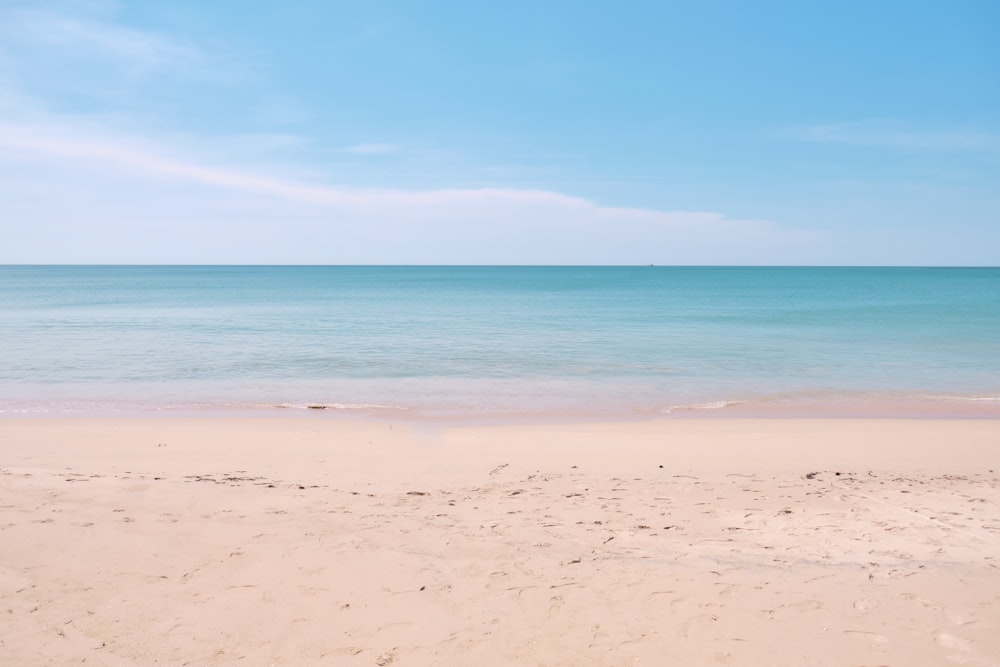 uma praia de areia com um céu azul e oceano no fundo