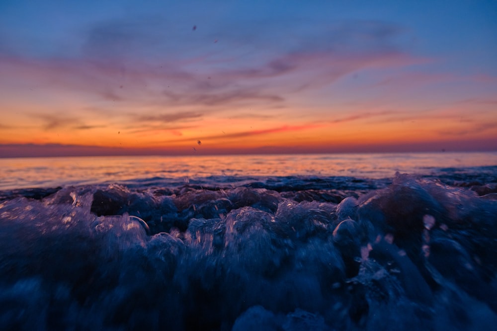 un coucher de soleil sur un plan d’eau avec des vagues