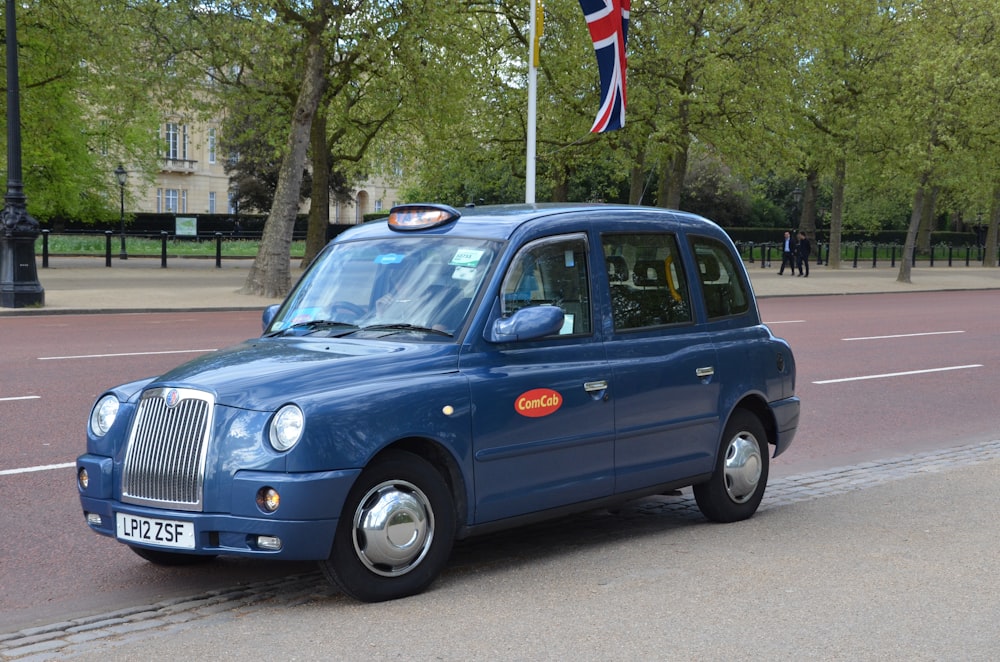 a blue taxi cab parked on the side of the road