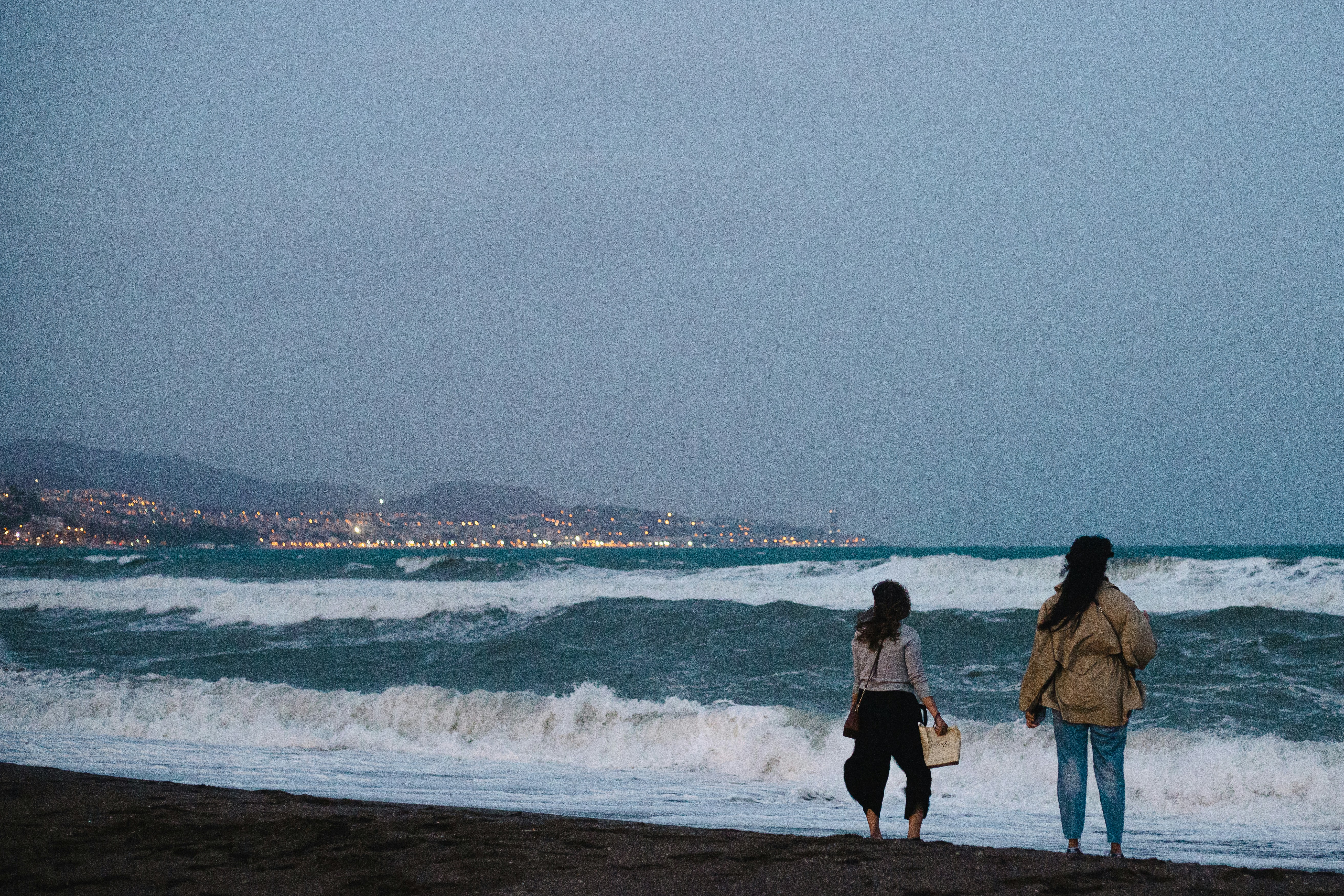 Una pareja de mujeres caminando por una playa junto al océano