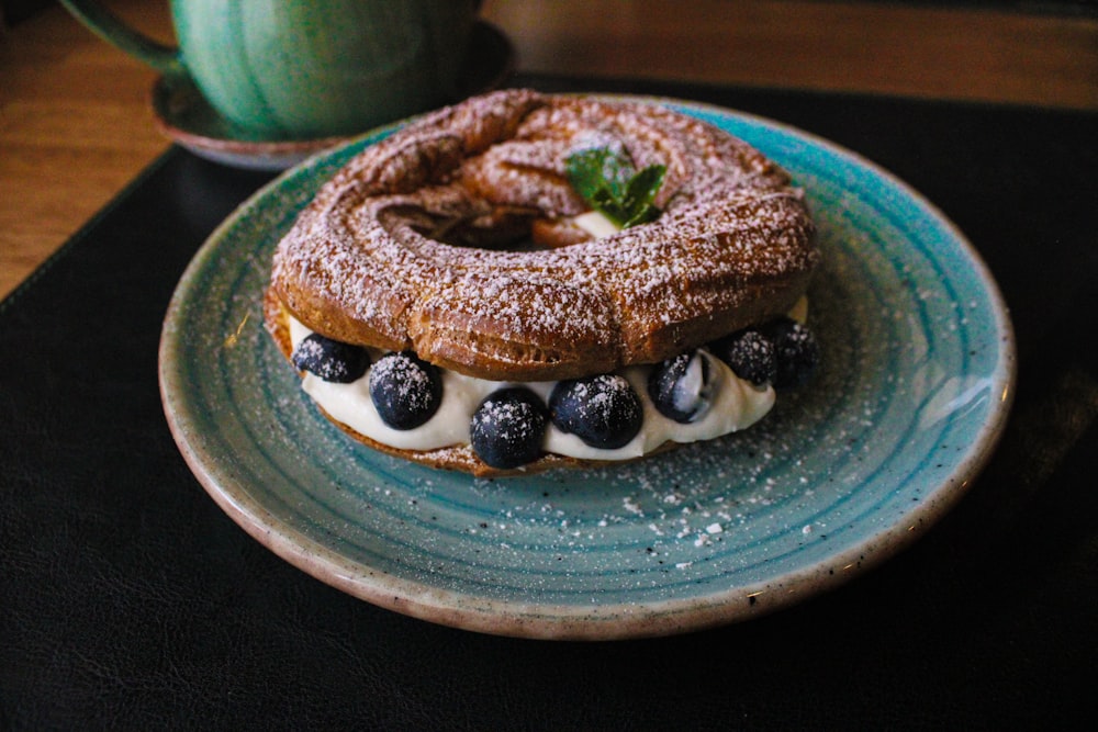 a blue plate topped with a pastry covered in powdered sugar