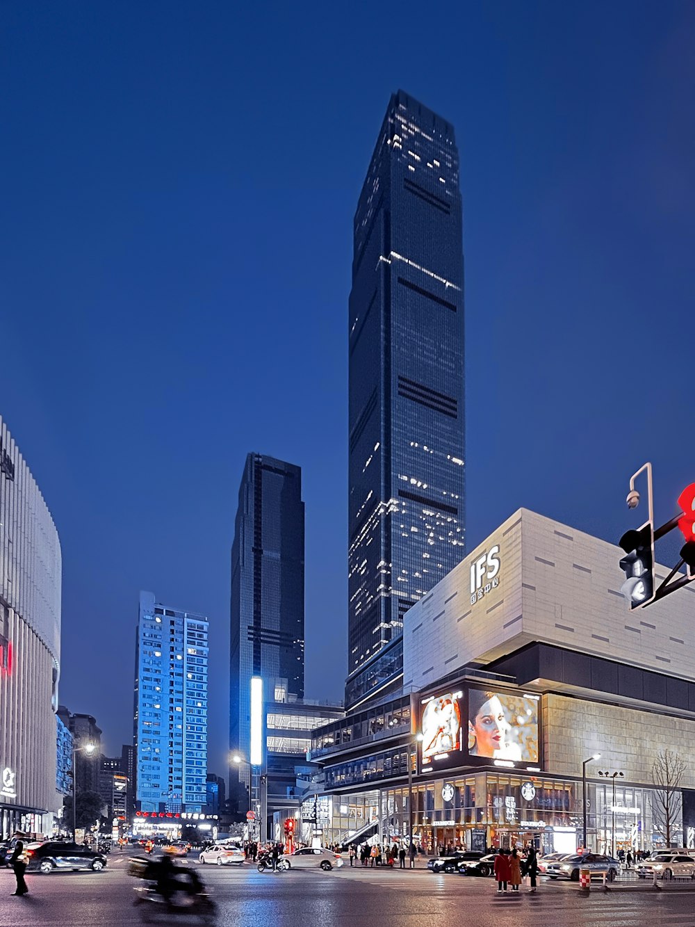 a busy city street at night with tall buildings