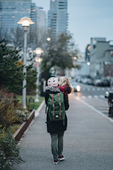 a woman walking down a street with a child on her back