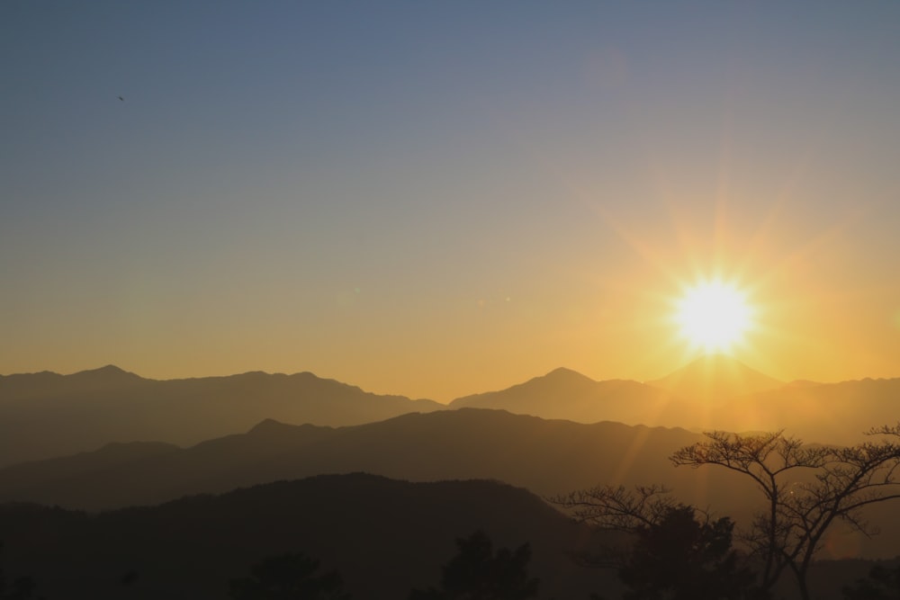 the sun is setting over a mountain range