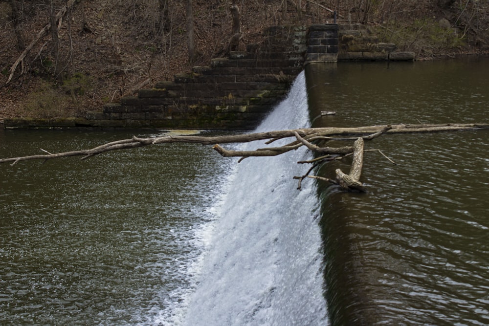 a man riding a surfboard next to a waterfall