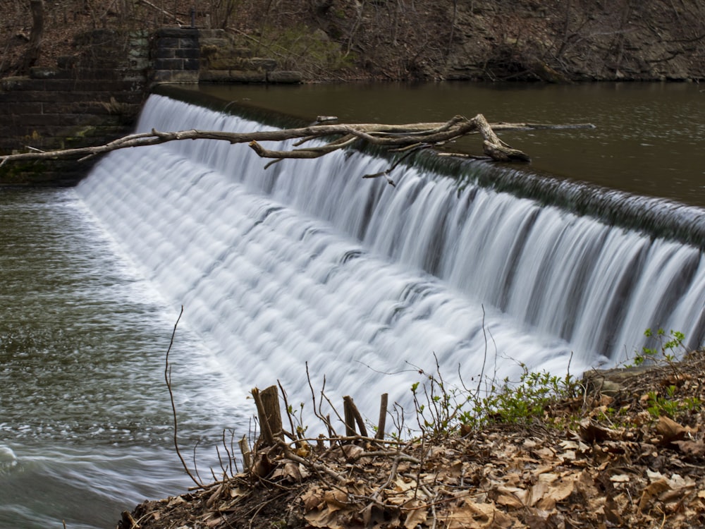 a large waterfall with a tree branch sticking out of it