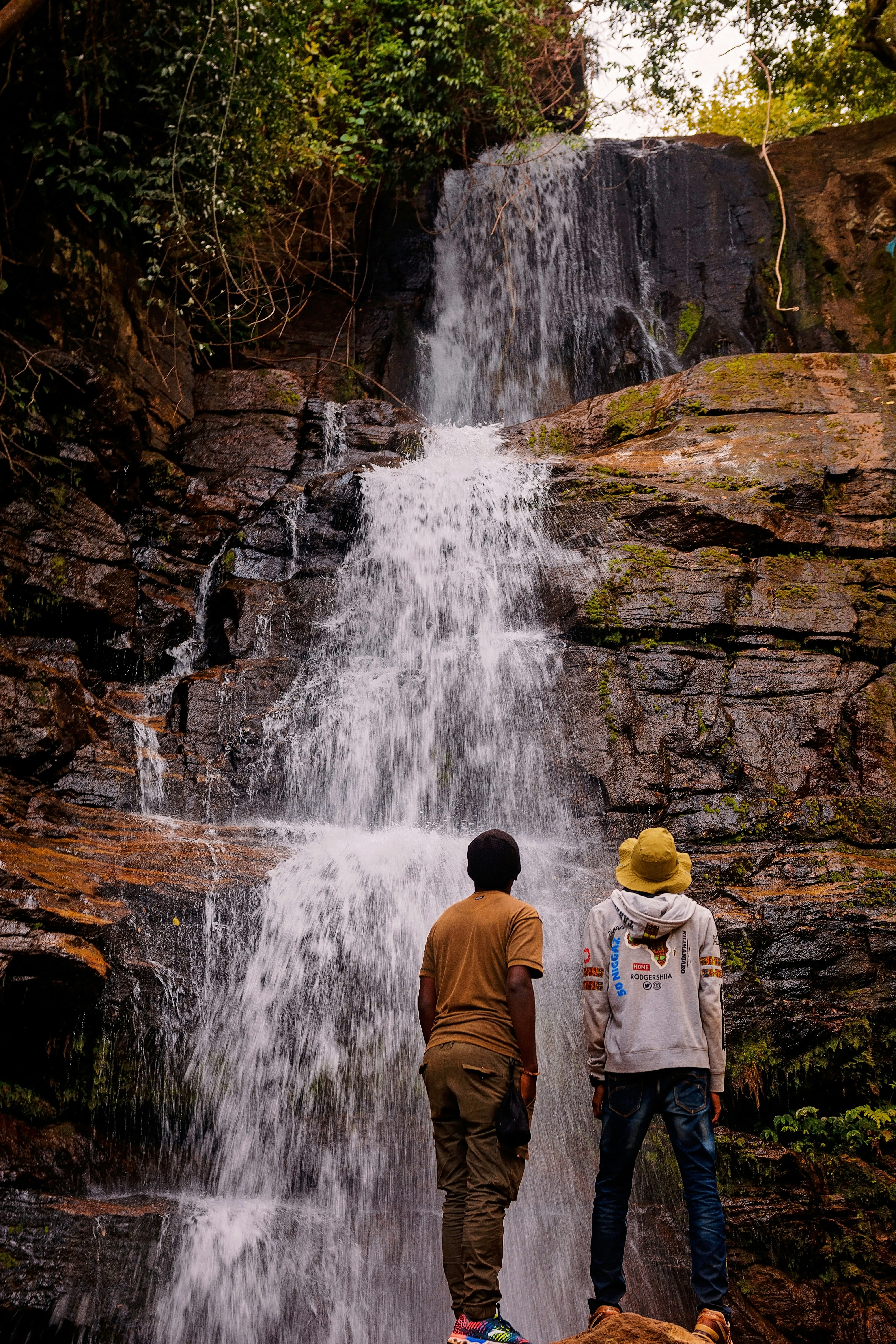 Un par de personas de pie frente a una cascada