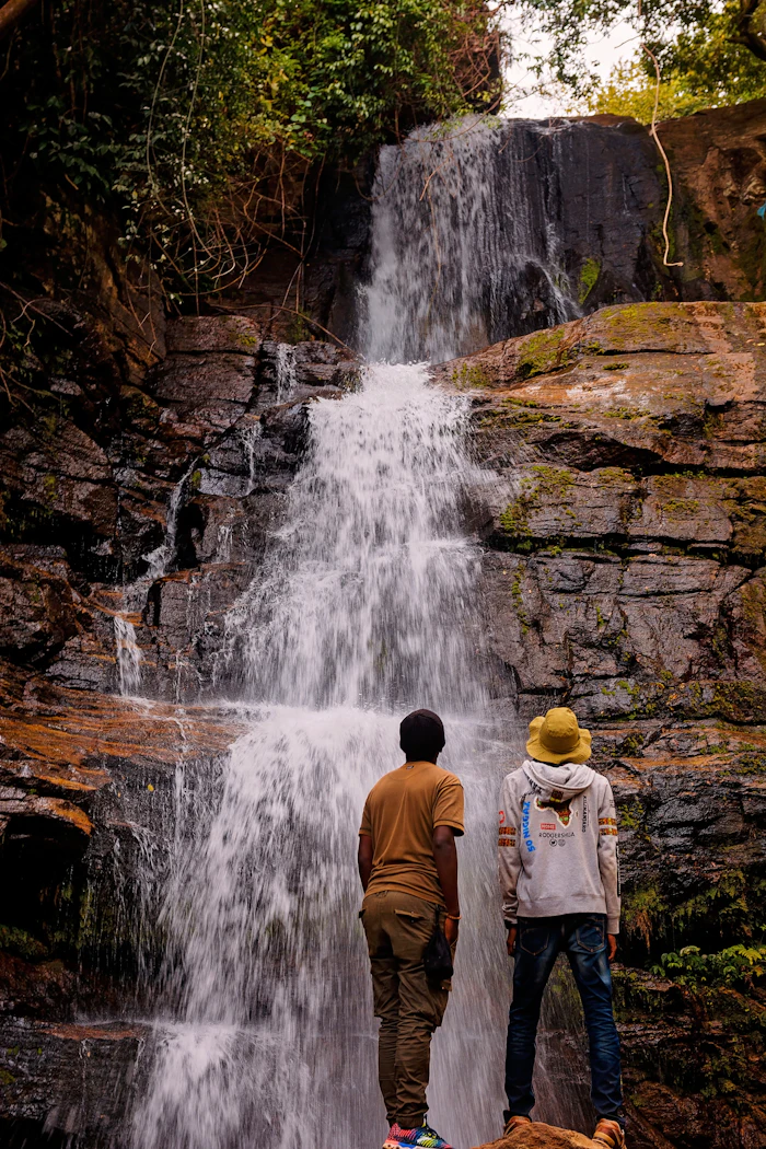 Two visitors in front of a waterfall