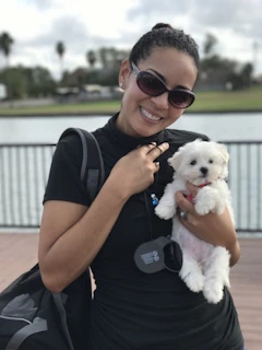 A happy customer holding their tiny teacup puppy outdoors on a sunny day.