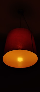 A sleek red therapy lamp glowing softly in a dark, cozy bedroom setting.