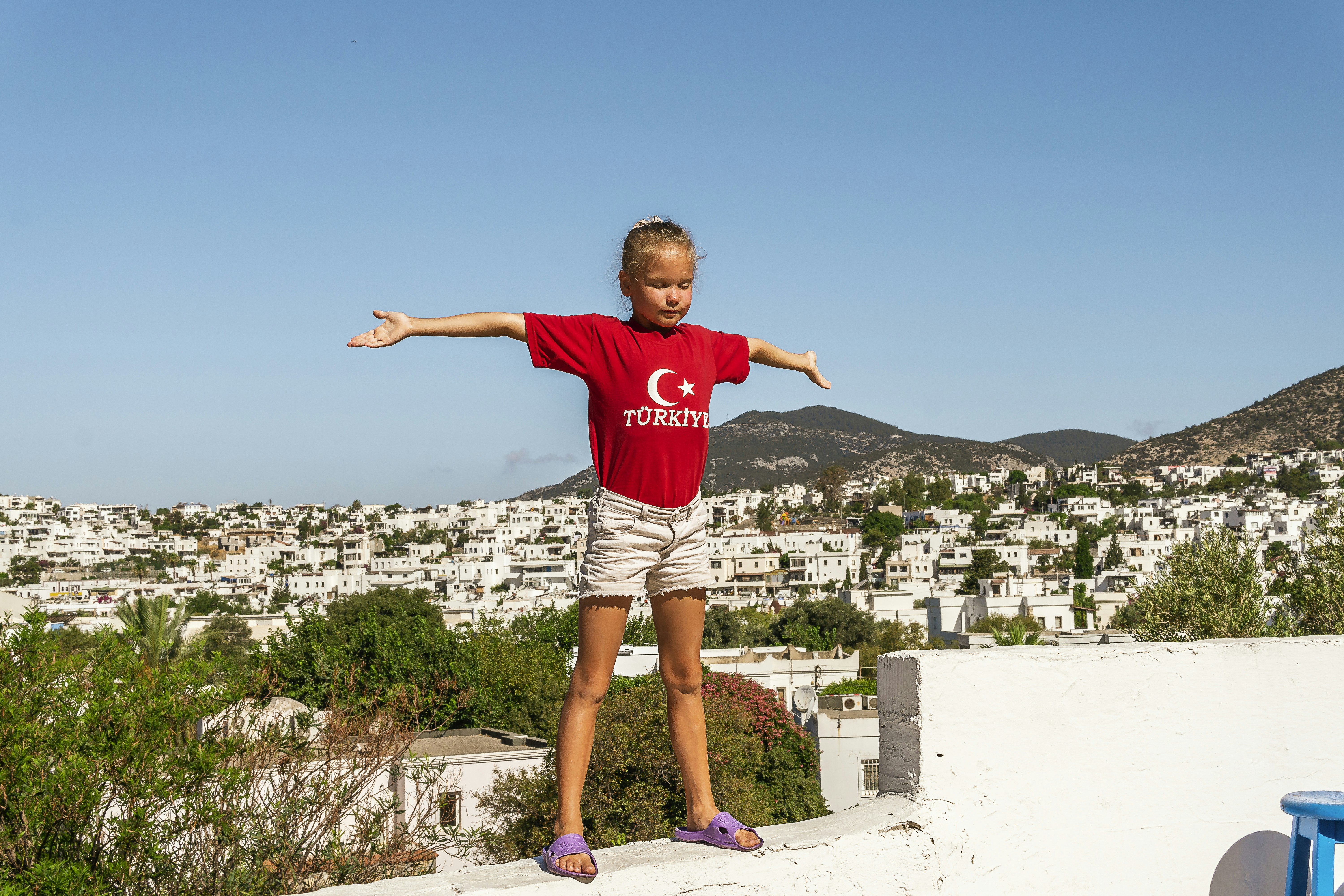 a little girl standing on a ledge with her arms outstretched