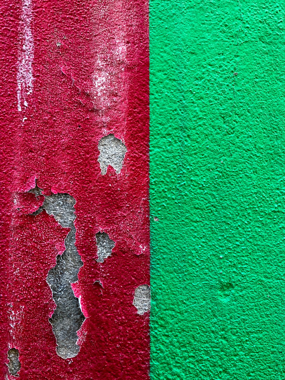 a red and green wall with peeling paint