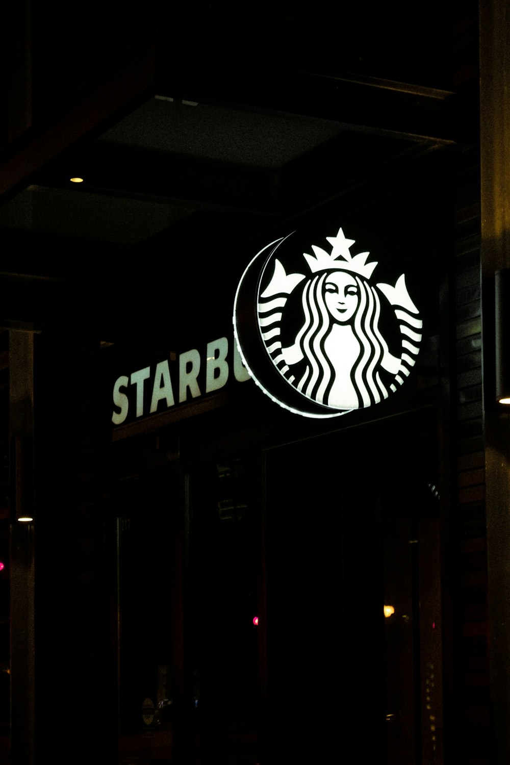a starbucks sign lit up in the dark