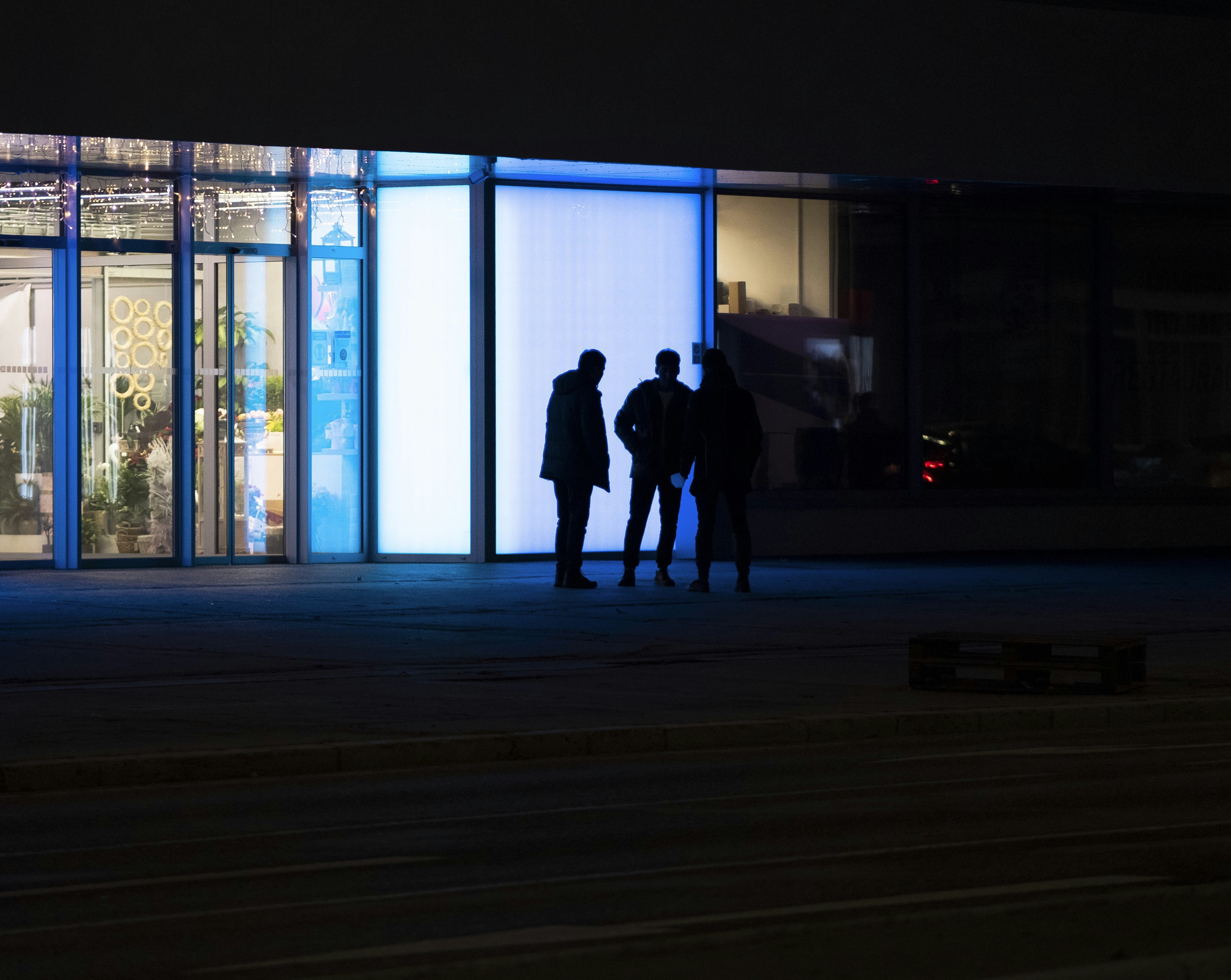 three people standing in front of a building at night