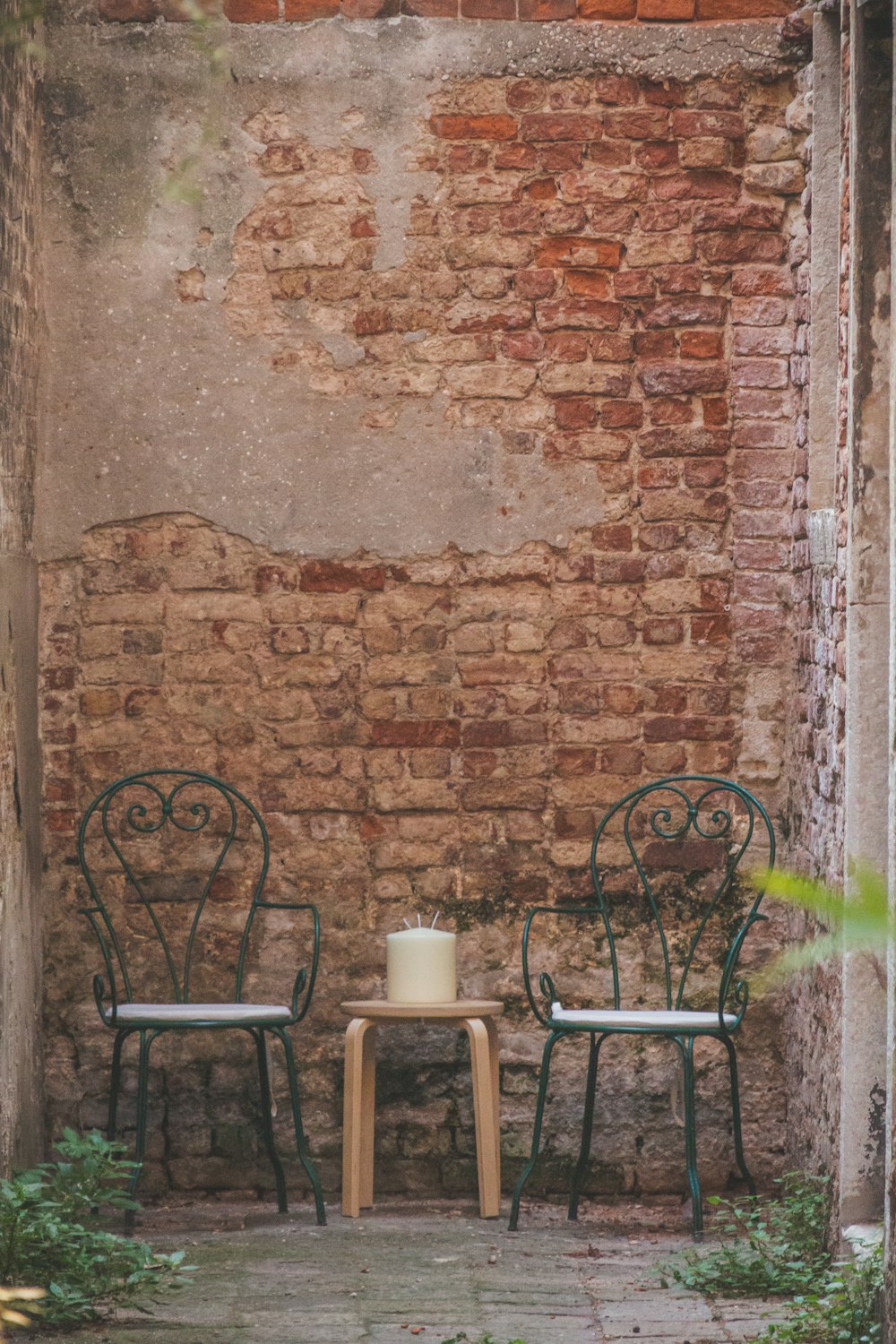 two chairs and a table in front of a brick wall