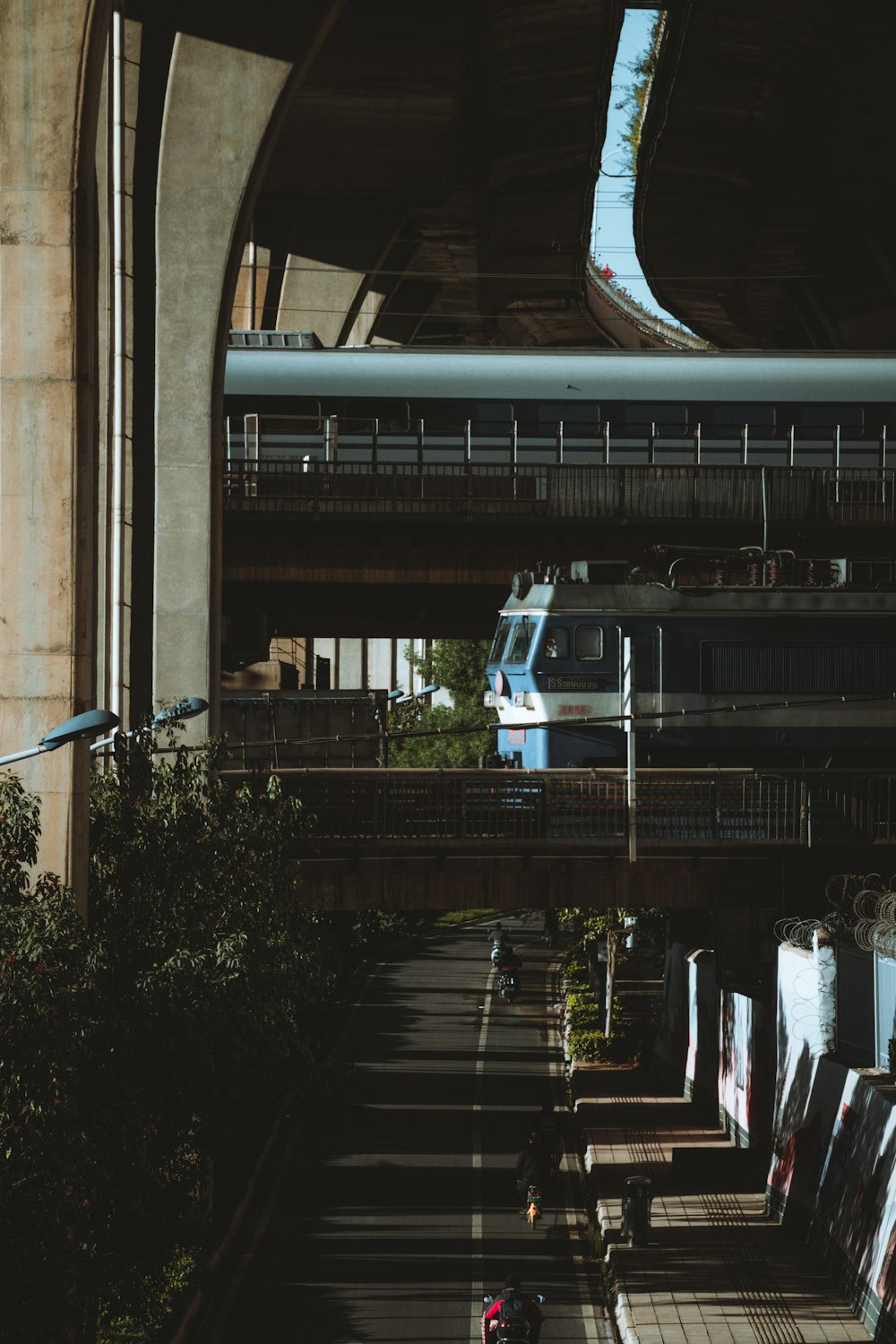 a train traveling under a bridge next to a tall building