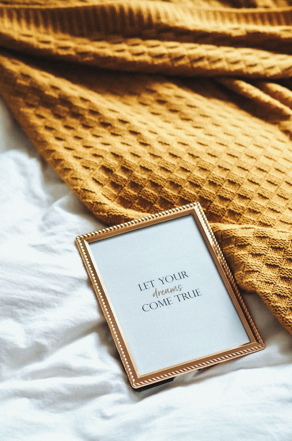 a picture frame sitting on top of a bed next to a blanket
