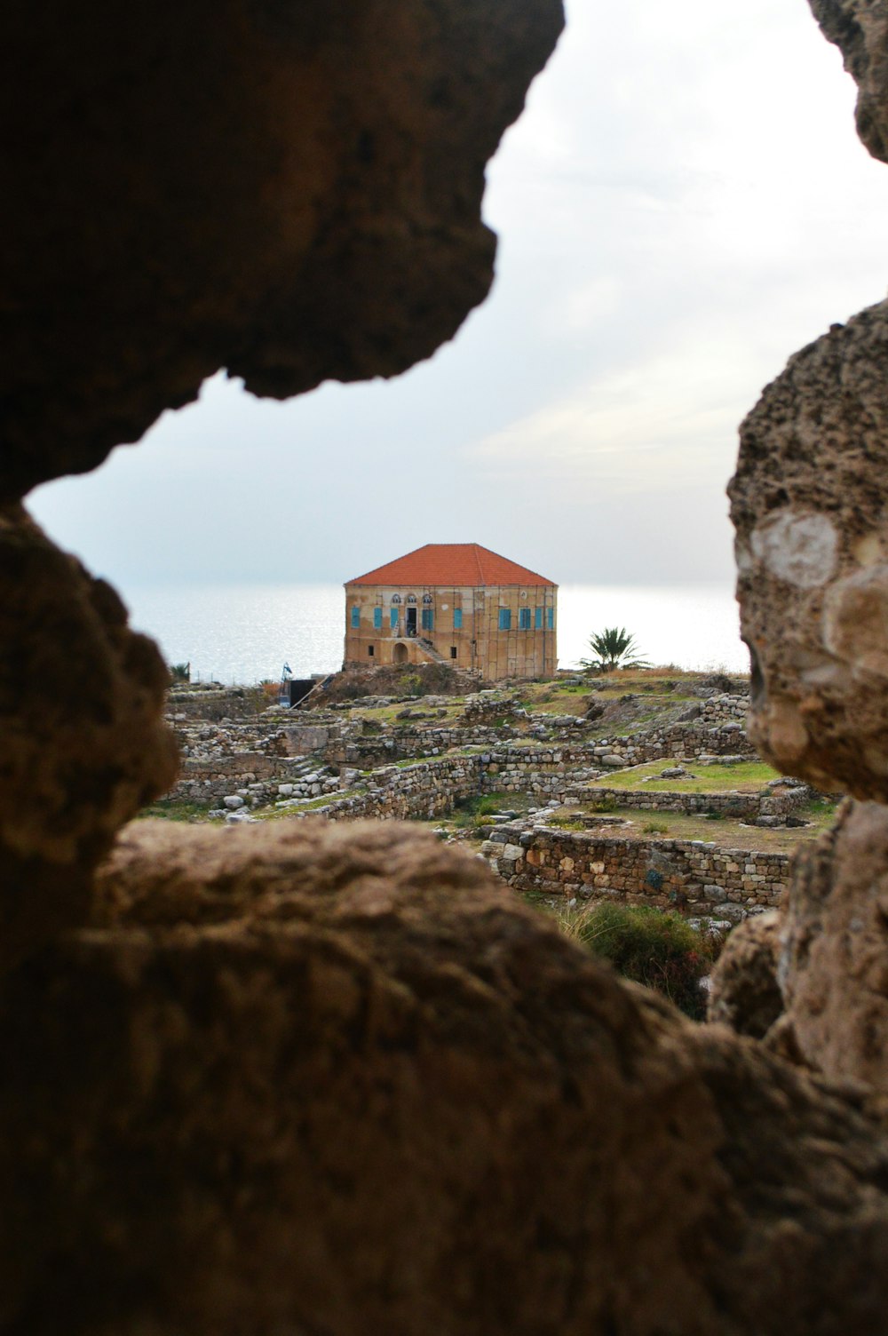 a house is seen through a hole in the rocks