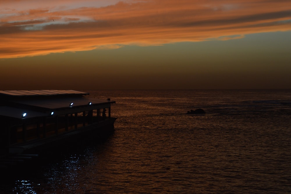 the sun is setting over the ocean with a boat in the water