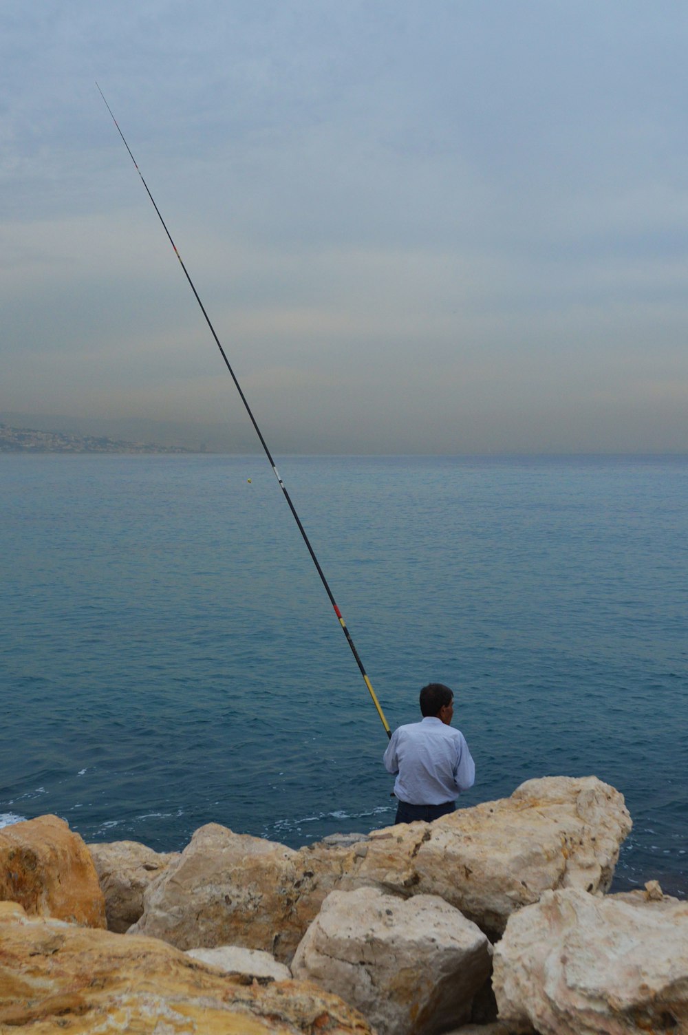 a man sitting on a rock with a fishing rod