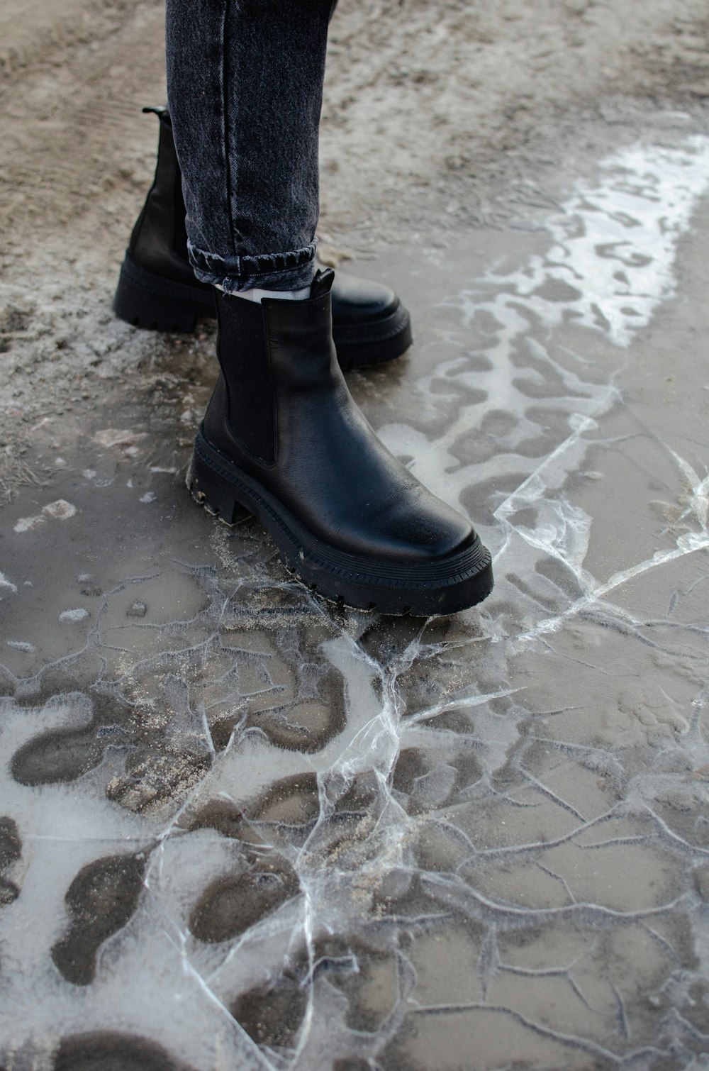 a person in black boots standing in a puddle of water