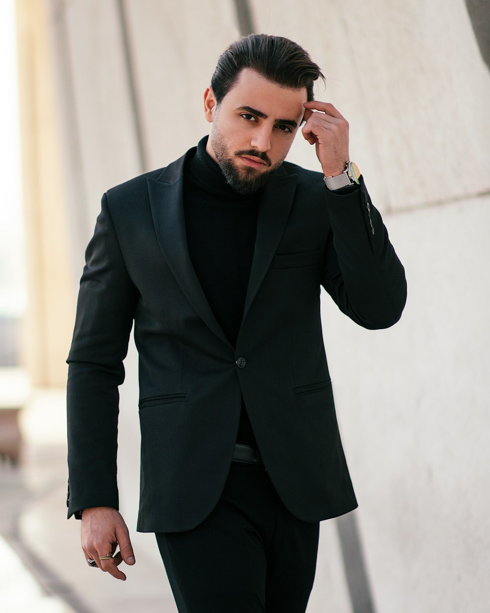 a man in a black suit walking down a street