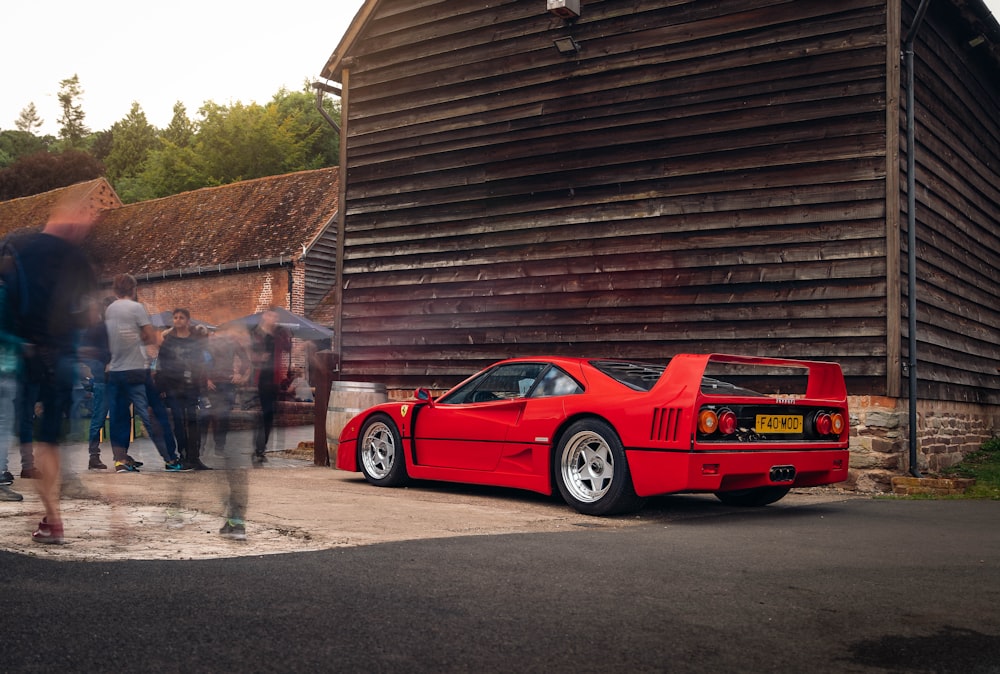 a red sports car parked in front of a barn