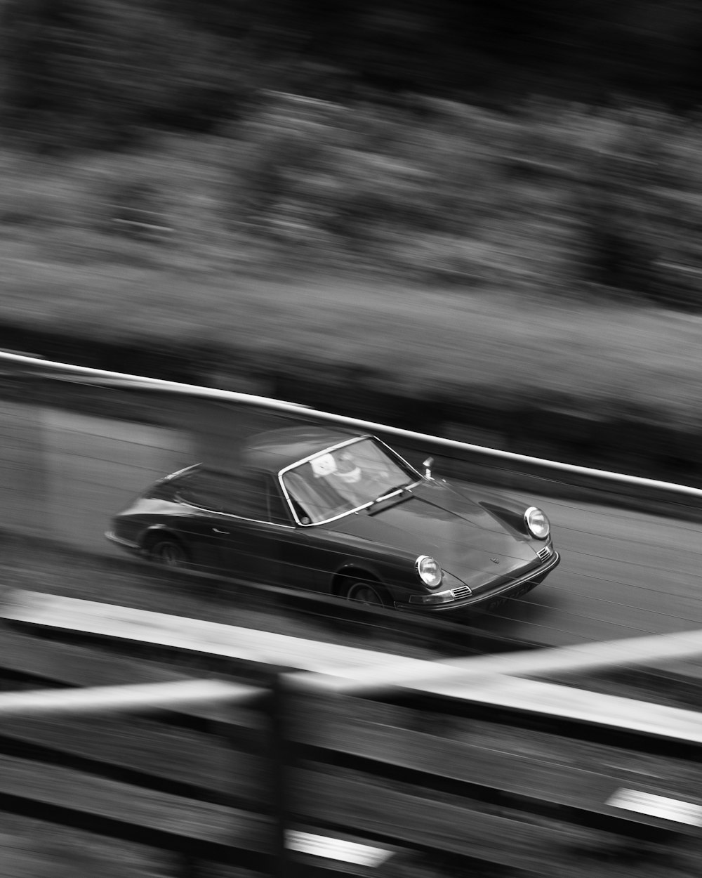 a black and white photo of a car driving on a road