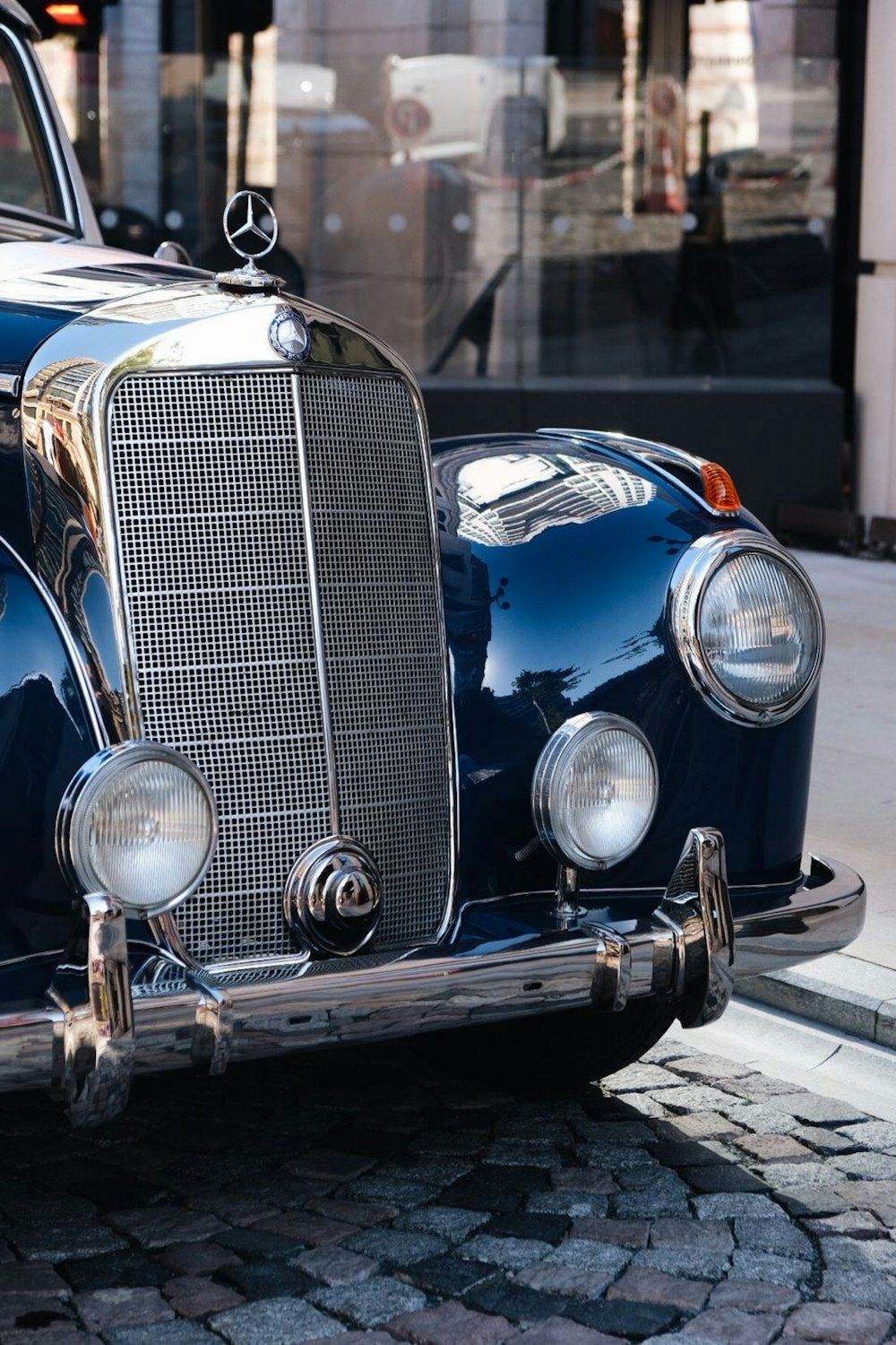 a classic car is parked on a cobblestone street