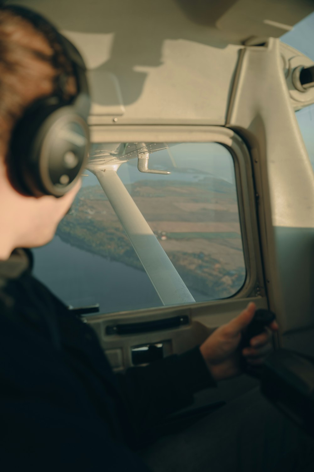 a person wearing headphones looking out the window of a plane