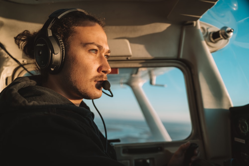 a man wearing headphones sitting in the cockpit of a plane