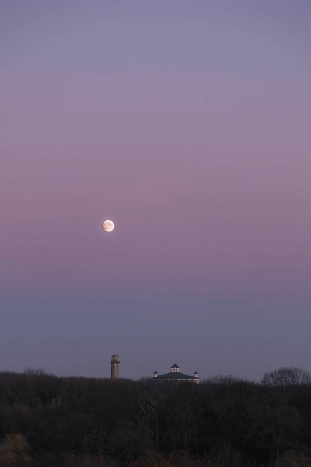 the moon is setting over a small building