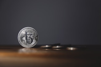 Close-up of a shiny gold coin and a silver bar side by side on a wooden surface.