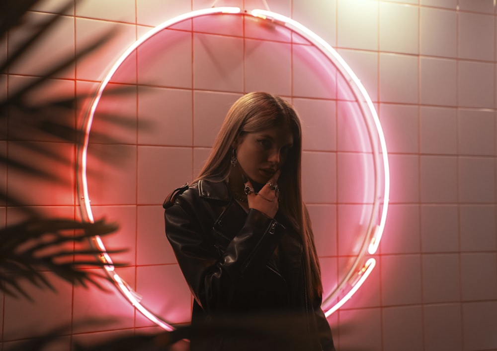 a woman standing in front of a neon sign talking on a cell phone