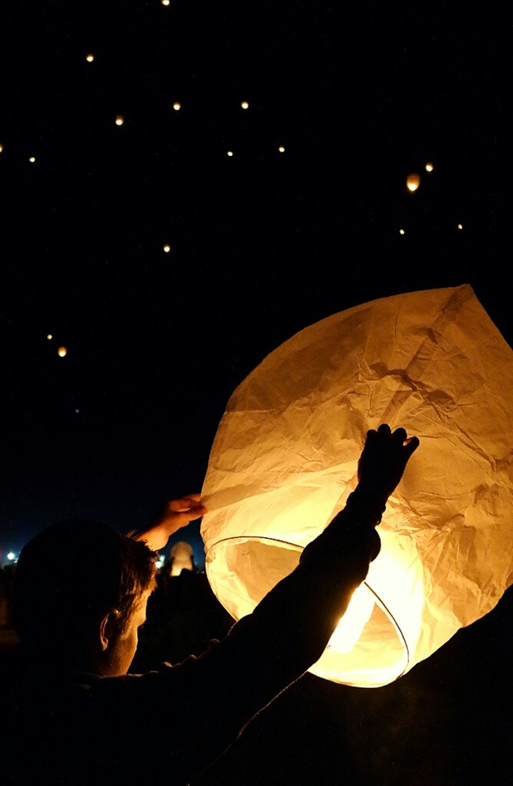 a person holding a paper lantern in the dark