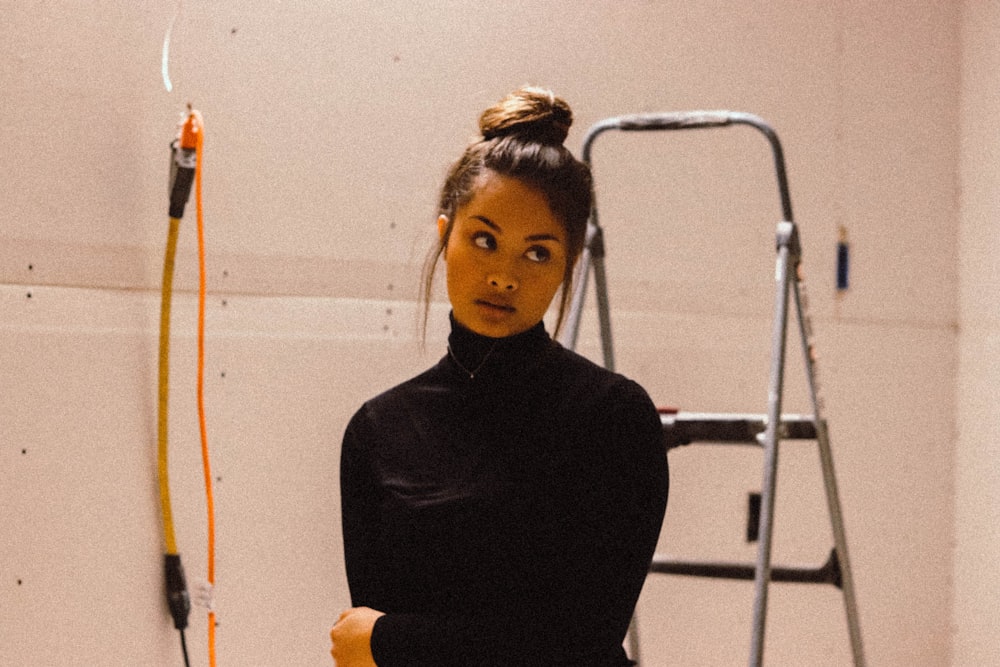 a woman standing in a room next to a ladder