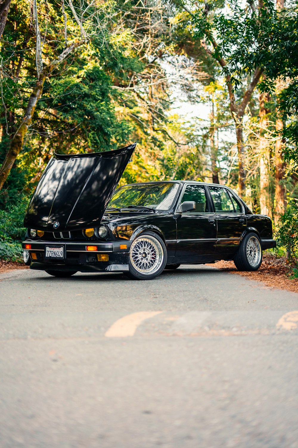 a car with its hood open sitting on the side of a road