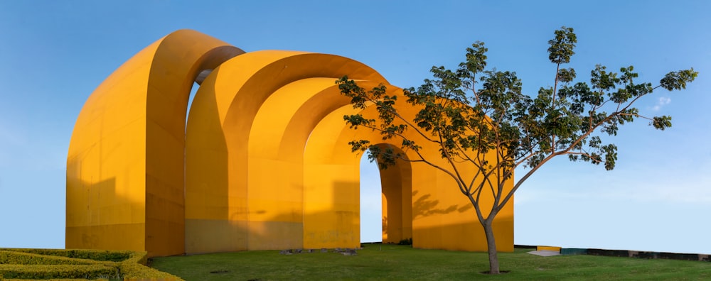 a large yellow structure with a tree in front of it