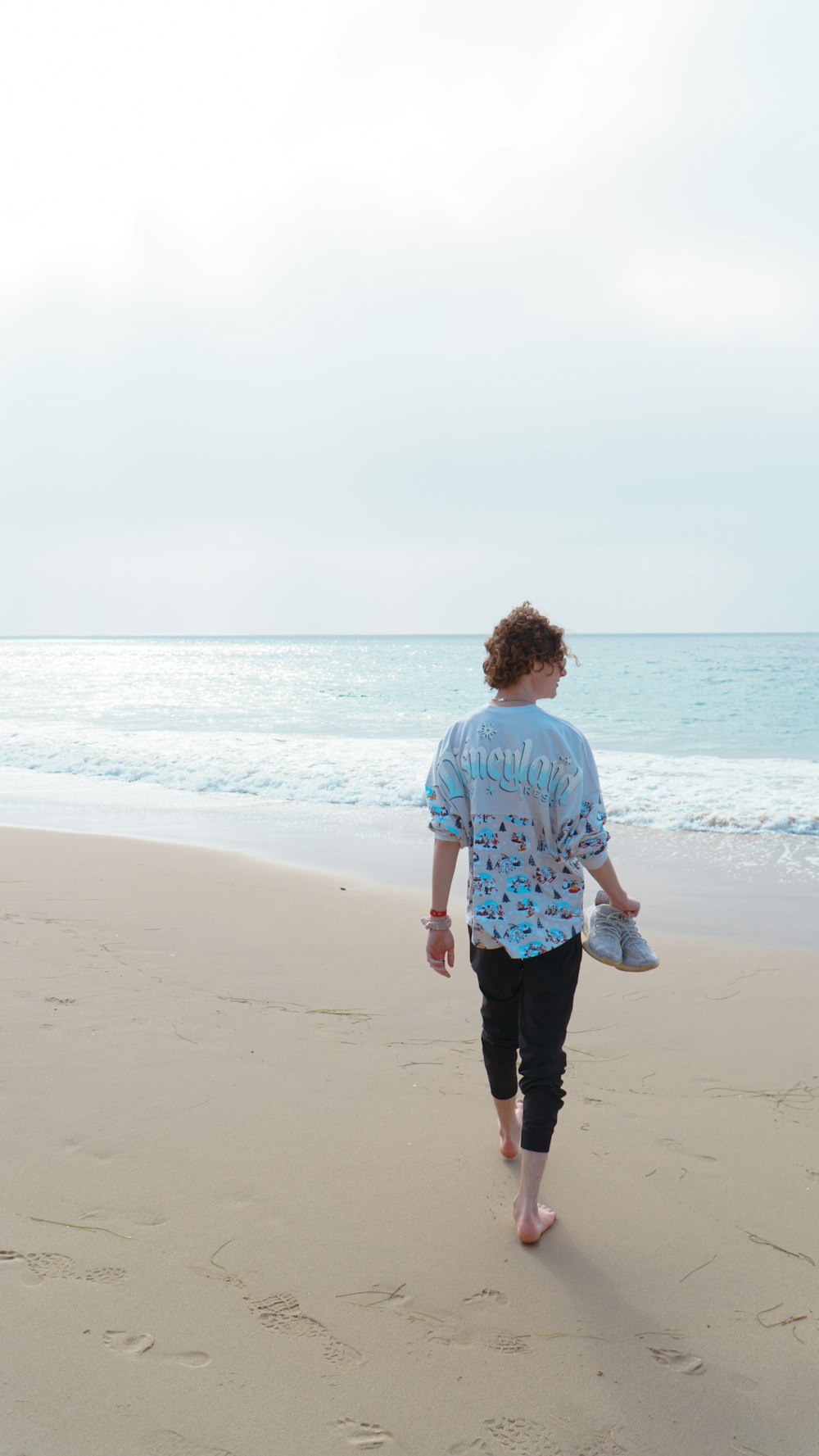 a woman walking on the beach with a frisbee